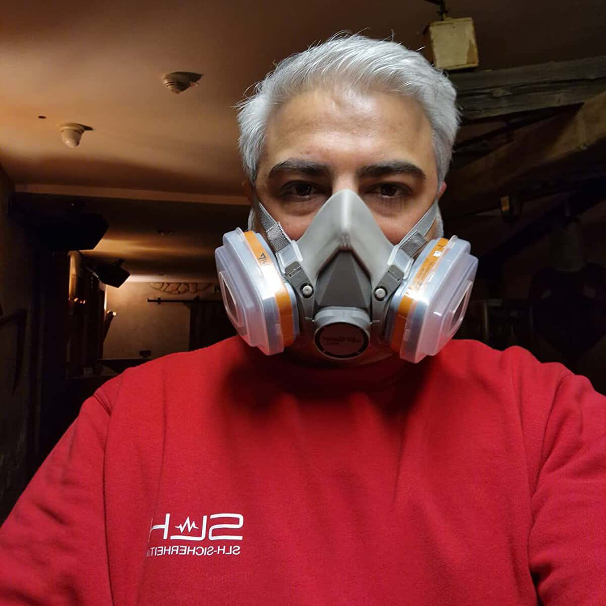 Protective respiratory mask worn by a man in a red sweatshirt indoors, emphasizing safety gear for health protection.