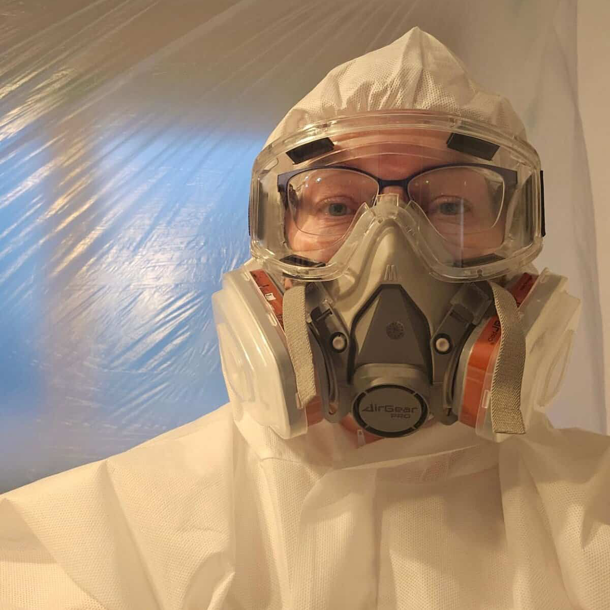 High-quality protective gear for air quality safety, person wearing full PPE including goggles and gas mask, airborne contamination protection, indoor hazardous environment safety gear, AirGearPro branding visible.